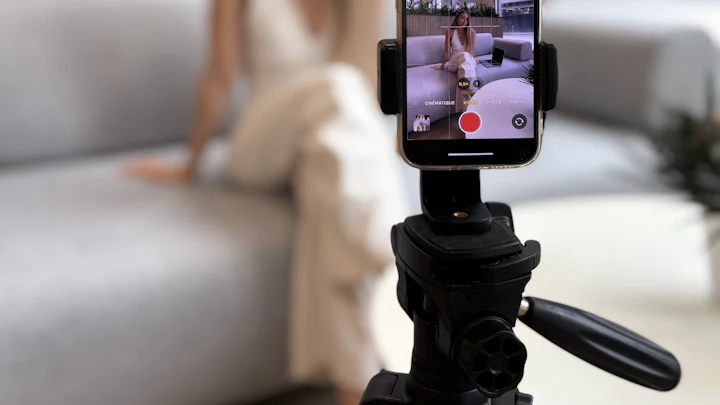 A creator filming herself on a smartphone mounted on a tripod