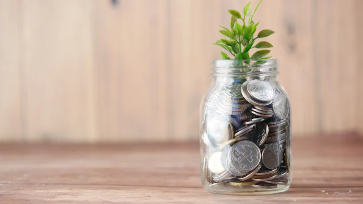 A glass jar of coins with a small plant growing from it
