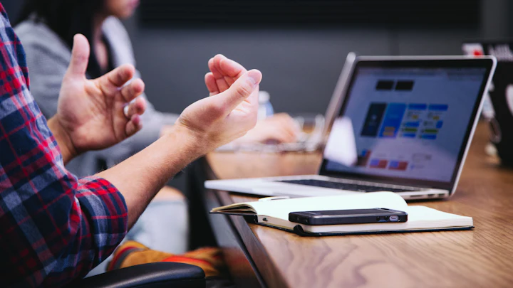 A person gesturing during a meeting around a laptop