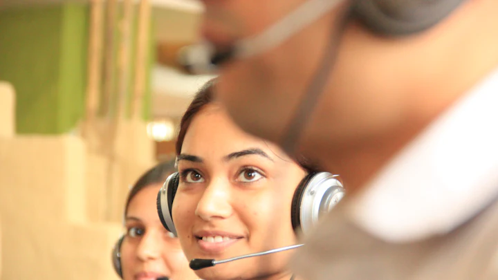 Two women wearing headsets working in a bright office