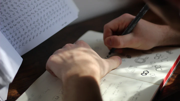 A designer sketching logo ideas on paper at a wooden desk