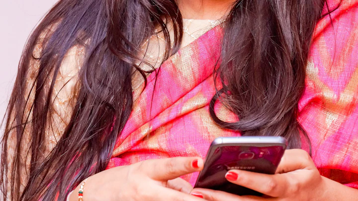 A woman in a pink sari looking at her smartphone